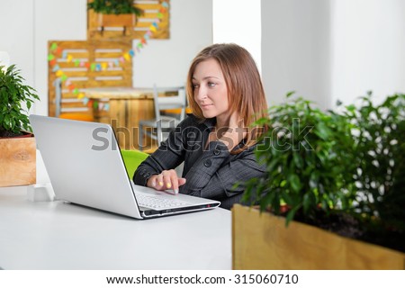 Business, technology and green office concept - young successful businesswoman with laptop computer at office. Woman using tablet computer