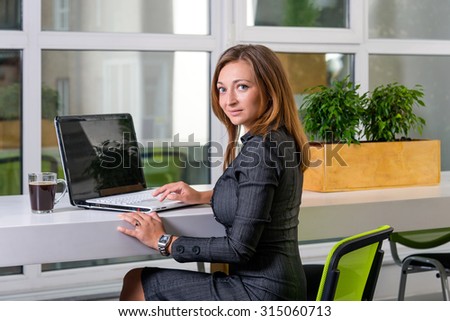 Business, technology and green office concept - young successful businesswoman with laptop computer at office. Woman using tablet computer or having a coffee break