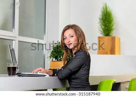 Business, technology and green office concept - young successful businesswoman with laptop computer at office. Woman using tablet computer