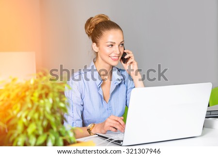Business, technology and green office concept - young successful businesswoman with laptop computer talking on the phone at office. Beautiful woman using tablet computer