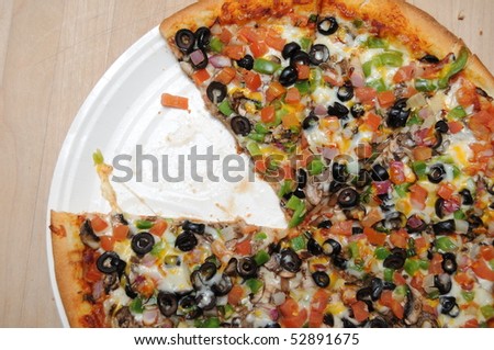 Pizza with black olives, green pepper, mushrooms, cheese, and ground beef hamburger meat with purple onions.