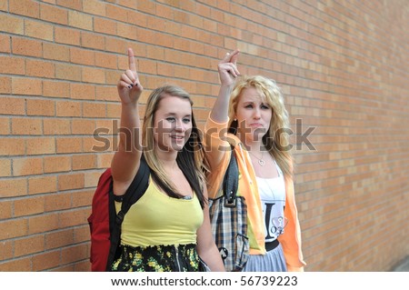 Two Teenage Girls Waving Their Raised Hands And Fingers Up Trying To ...