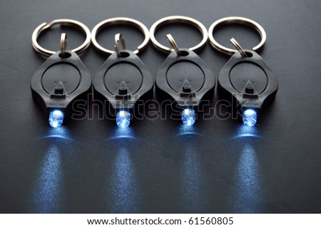 Miniature LED keychain lights on a black surface with shallow depth of field.