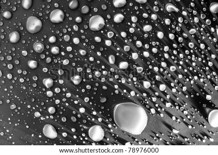 Water drops on a dark surface. The water droplets are very bright and contrast well with the dark background