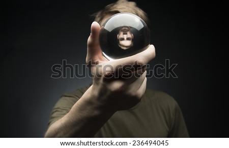 Young man holding a clear transparent crystal glass ball in their hand