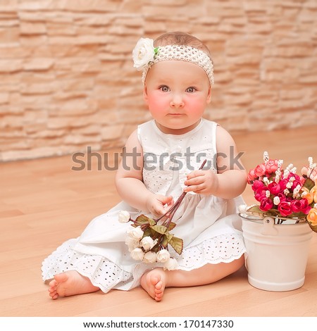 Little girl sitting on the floor with a bunch of roses and smiling / Laughing baby