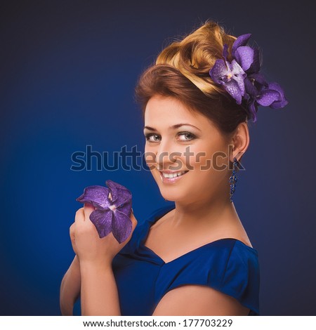 Attractive plus size model. Portrait of beautiful curly young blond woman with flowers in her hair posing on violet.
