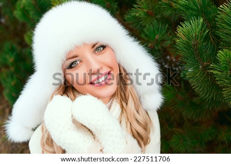 Woman in a hat, mittens, scarves, sweaters, fur in winter fir forest