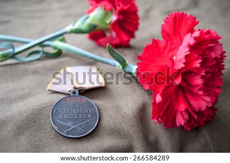Soviet Medal for Combat Service and two red carnations. Still life dedicated to Victory Day. 9 May.