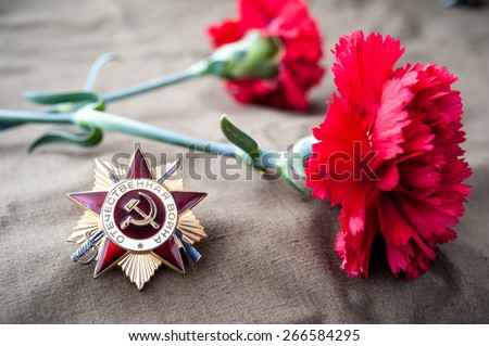 Order of the patriotic war 1st class and two red carnations. Still life dedicated to Victory Day. 9 May.
