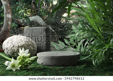 Natural stone and concrete podium in tropical forest with flowers. Empty showcase for packaging product presentation. Background for cosmetic products, scene with green leaves. Mock up pedestal.