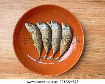 Four ried mackerels on the plate. The mackerel fish were cooked by frying put. And them together on a orange plate on wooden table. Imagine de stoc © 
