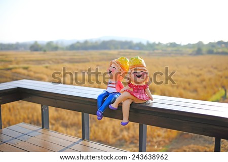 A girl and a boy dolls, sitting by fields background . (love concept)