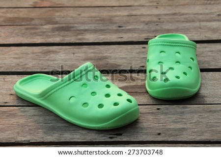 Green rubber slippers on old wooden floor.