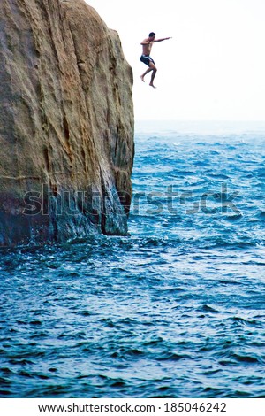 Man jumping from the rock into the sea
