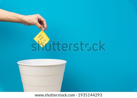 Hand holds a sticker with the inscription yes. White empty basket on blue background Stockfoto © 