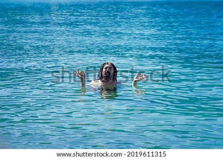 A man with dreadlocks in a relaxed Om position in turquoise water. Relaxation and enlightenment. 商業照片 © 