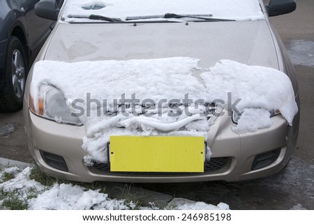 car covered with snow with a yellow label instead of the number