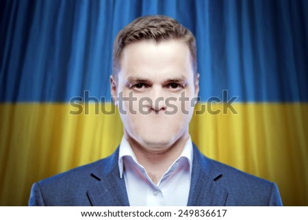 Symbol of censorship and freedom of speech: a young man without a mouth on a background of the national flag of Ukraine