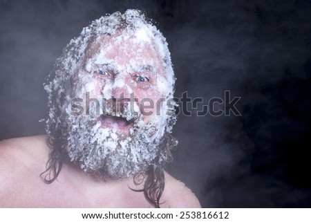 Russian extreme: a naked man in the snow with frozen beard and hair in the clouds of steam