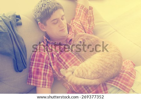Man lying on the sofa and and on his belly lying a cat. - instagram style
