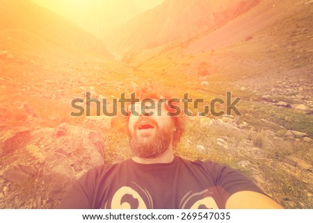 Bearded man makes selfie in the mountains with a frightened look - instagram style