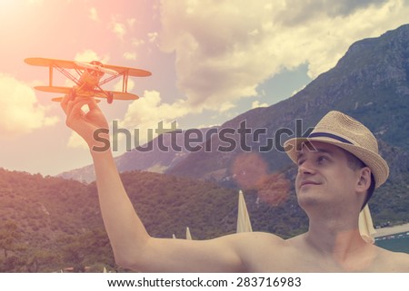 Toy airplane in hand of young man- a symbol of travel and dreams