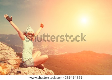 Woman sitting on the edge of the cliff in lotus position with opened hands