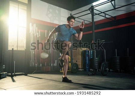 Strong young athlete fit man running in fitness gym. The man with sportswear showing his strength muscular in body. Bodybuilding exercise and sport workout training concept.