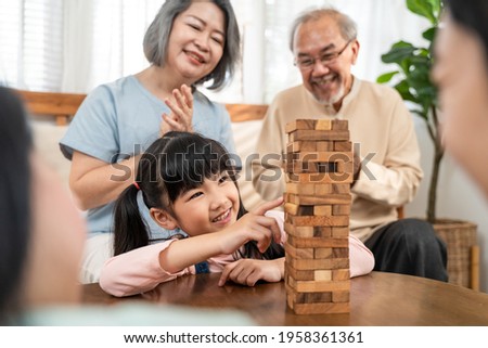 Similar – Image, Stock Photo Excited girl playing jenga game with her mom in play room. Girl removing one block from stack and placing it on top of tower. Game of skill and fun. Family time