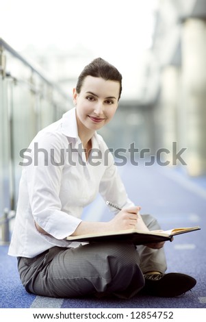 Businesswoman is sitting on the floor with a calendar on hewr lap