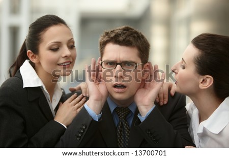 Businessman listening to advice from two woman whispering to ear in the office