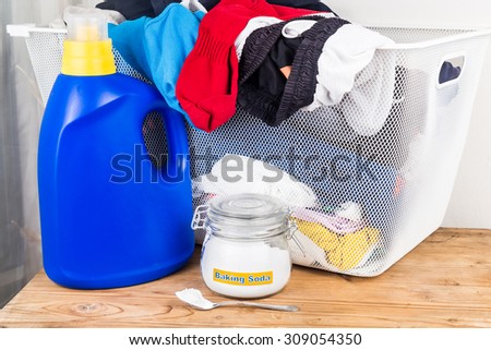 Baking soda with detergent and pile of dirty laundry