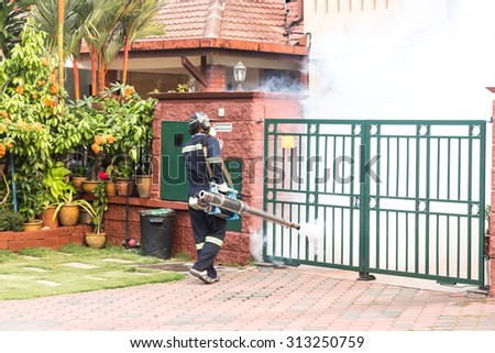 Worker fogging residential area with insecticides to kill aedes mosquito, carrier of dengue virus