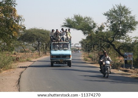 An over-loaded truck carrying people on the roof in Gujarat State, India.This practise though illegal is common in many parts of rural India due to lack of public transportation.