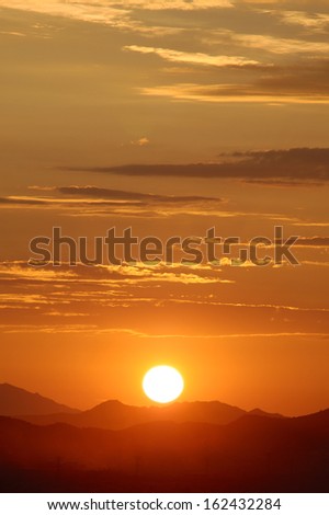Sun setting over hills (vertical)