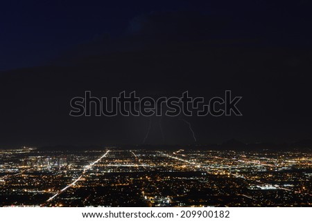 Phoenix city lights at dusk with three lightning strikes