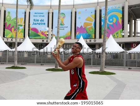 RIO DE JANEIRO, BRAZIL - May 26, 2014: Brazilian fan holding a replica of the FIFA World Cup Trophy in front of Maracana 16 days before the World Cup opening ceremony on June 12, 2014 in Sao Paulo.