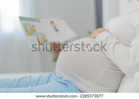 Pregnant woman is reading a story book to her baby. Reading to your child improves the brain and auditory development of the unborn child. love, family, strengthens, bonds, intelligence. Stockfoto © 