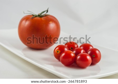 big tomato vs. small tomatoes in white background