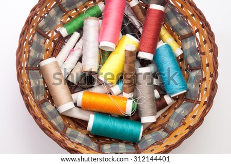 Colorful sewing thread in a wicker basket.