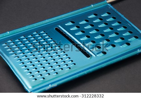 Blue cheese grater on a black background.