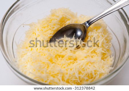 Grated cheese in a crystal bowl with spoon.