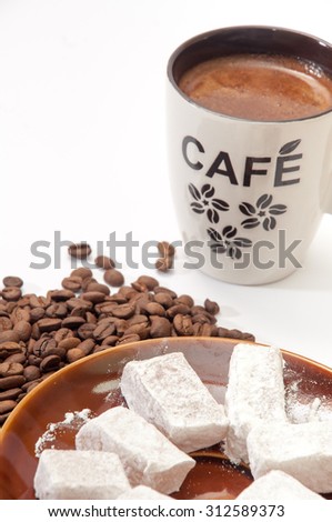 Turkish delight in a focus with raw coffee beans and cup of coffee in the background.