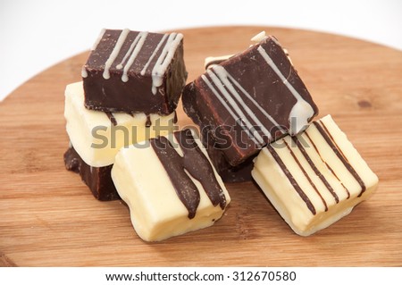 Black and white chocolate cakes on a kitchen wooden board.