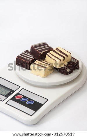 Black and white chocolate cakes on a kitchen scale.