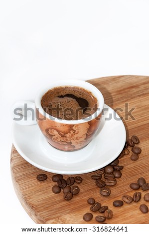 Cup of coffee with spilled coffee beans on the wooden board