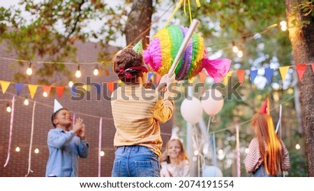 Children celebrating birthday in park. Group of children smash pinata with a bat at birthday party. Children having fun and playing Сток-фото © 