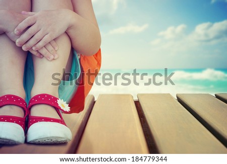 Little girl  sitting on the wooden deck