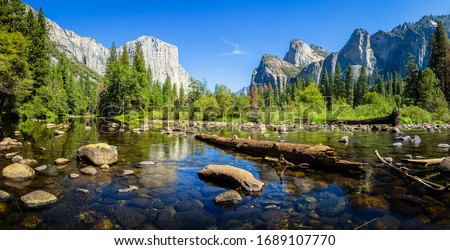 Scenic panoramic view of famous Yosemite Valley with El Capitan rock climbing summit and idyllic Merced river on a beautiful sunny day with blue sky in summer, Yosemite National Park, California, USA